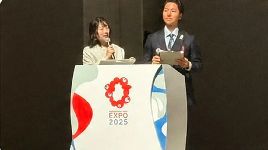 EXPO 2025のロゴ入り演台で司会をする山原慎也