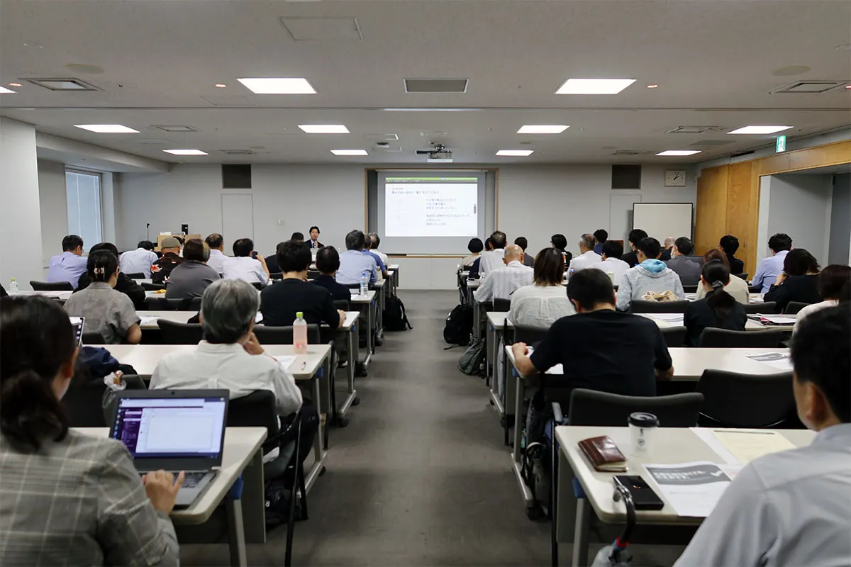 会議室で参加者がスクリーンのスライドを見ながら受講している様子